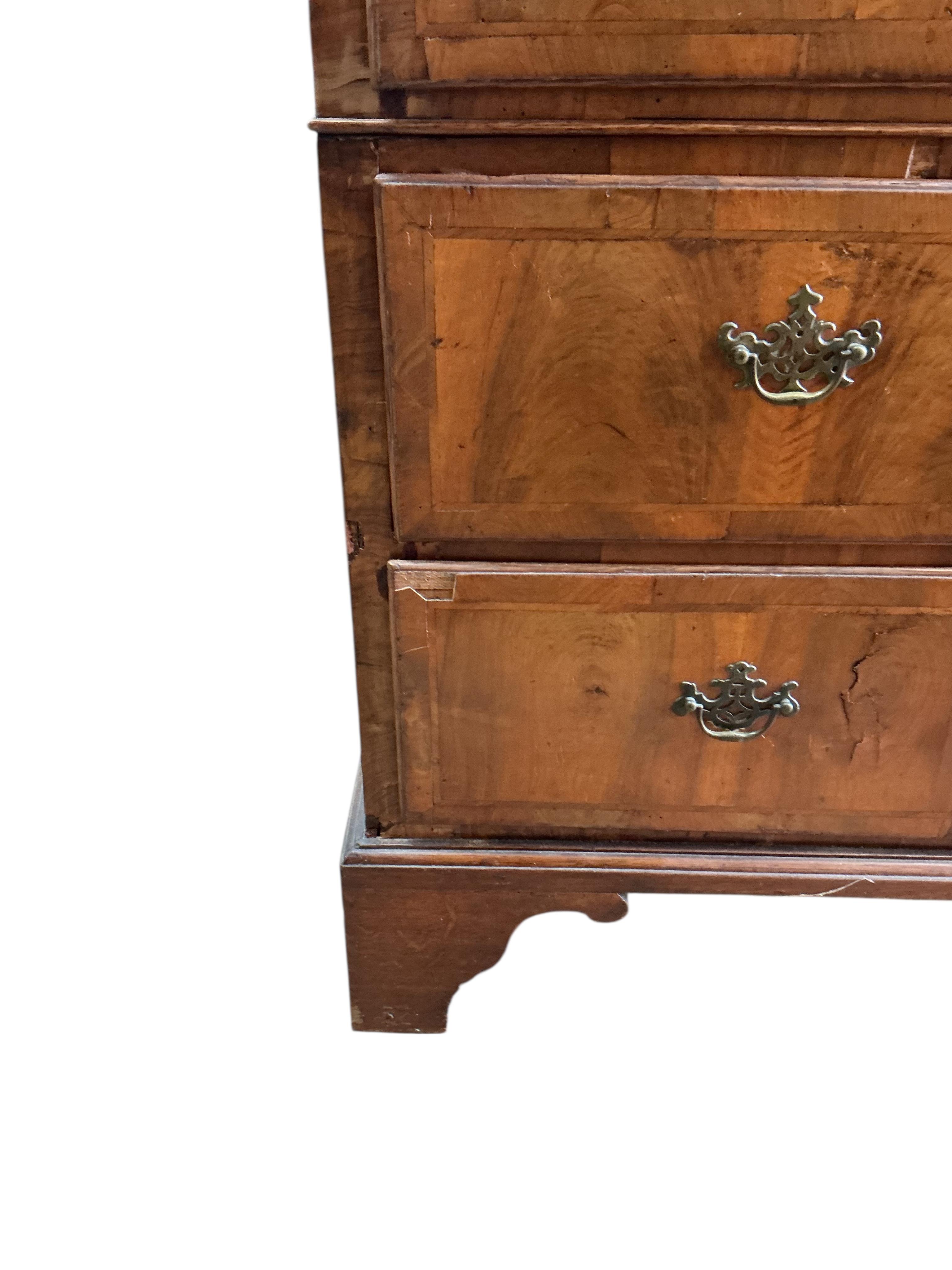 An early 18th century feather banded walnut and pine two section chest of drawers, on later bracket feet and with losses, width 96cm, depth 52cm, height 135cm